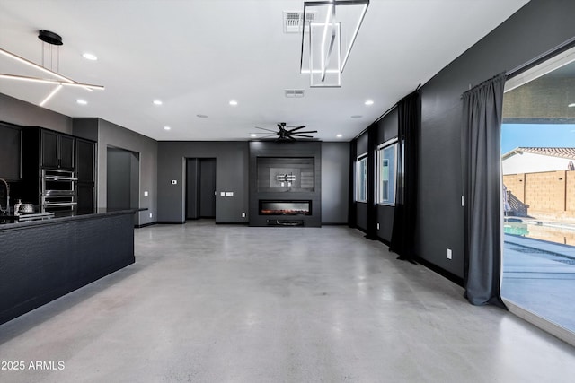 living room featuring ceiling fan, sink, and a fireplace