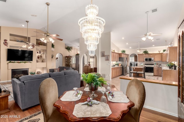 dining room with built in shelves, light hardwood / wood-style floors, and vaulted ceiling