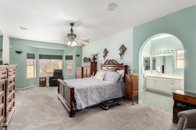 carpeted bedroom with ceiling fan, ensuite bath, and sink