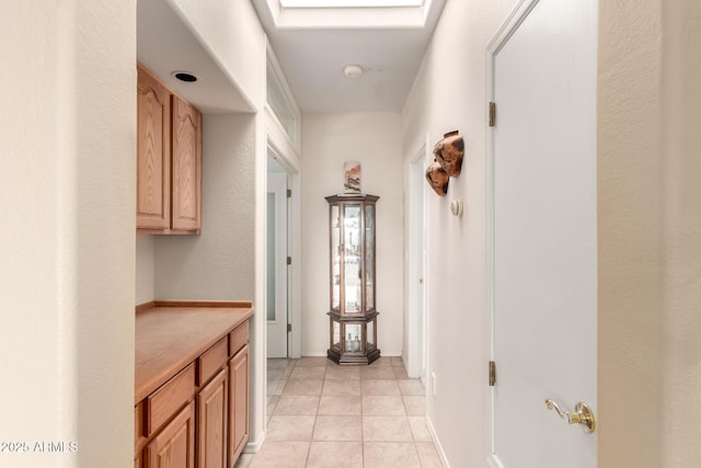 hall featuring light tile patterned flooring and a skylight