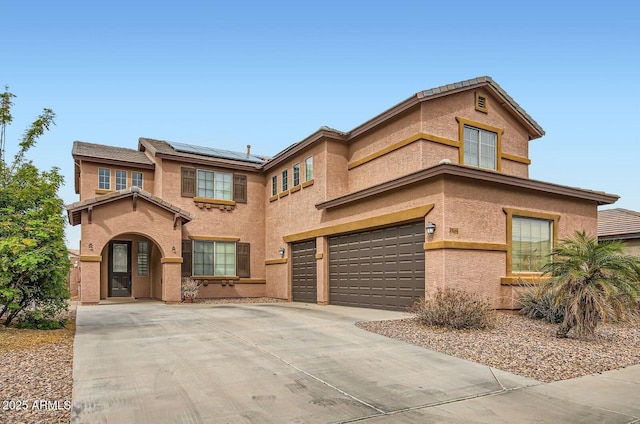 view of front of home featuring a garage, driveway, stucco siding, and roof mounted solar panels