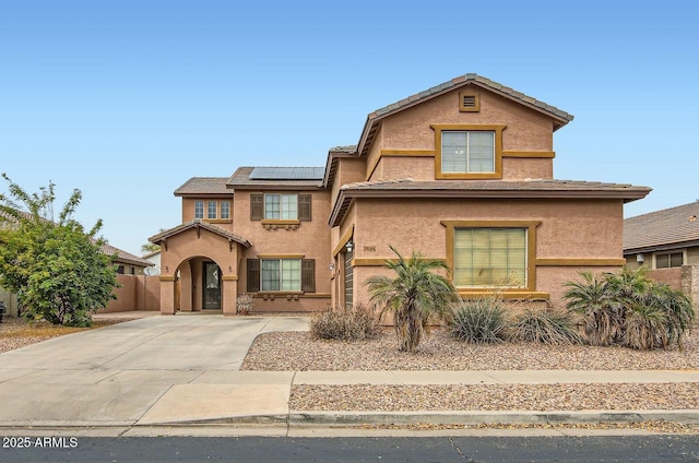 view of front of property featuring solar panels, fence, driveway, and stucco siding