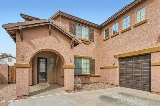 view of front of home with a garage, concrete driveway, a gate, and stucco siding