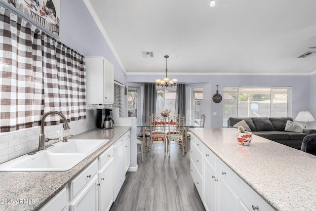 kitchen featuring visible vents, ornamental molding, and a sink