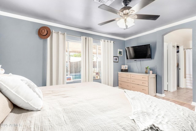 bedroom featuring crown molding, arched walkways, and ceiling fan