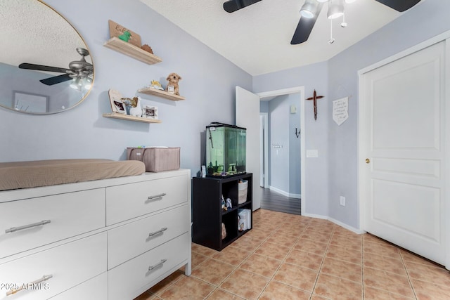 bedroom with light tile patterned floors, a textured ceiling, a ceiling fan, and baseboards