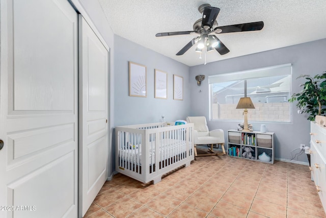 bedroom featuring a nursery area, light tile patterned flooring, a closet, and a textured ceiling