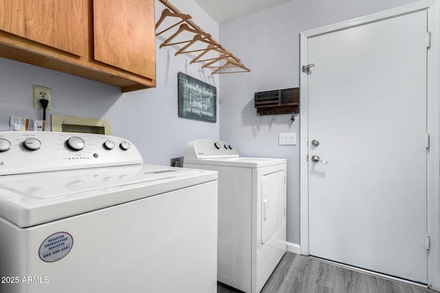 laundry room featuring cabinet space, washing machine and dryer, and light wood finished floors