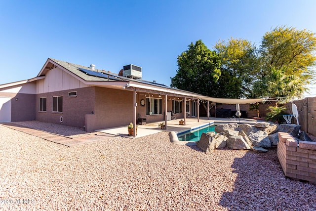 back of house featuring a fenced in pool, central air condition unit, roof mounted solar panels, a fenced backyard, and a patio