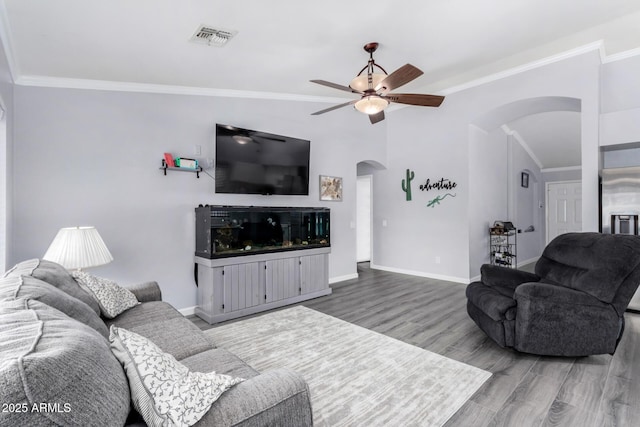 living area with a ceiling fan, wood finished floors, visible vents, arched walkways, and ornamental molding