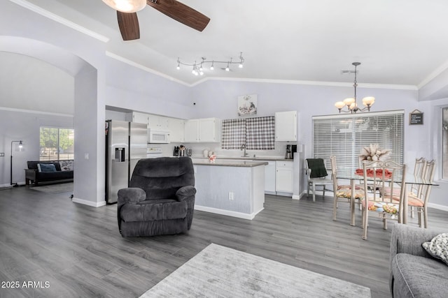 living room with vaulted ceiling, wood finished floors, crown molding, and ceiling fan with notable chandelier