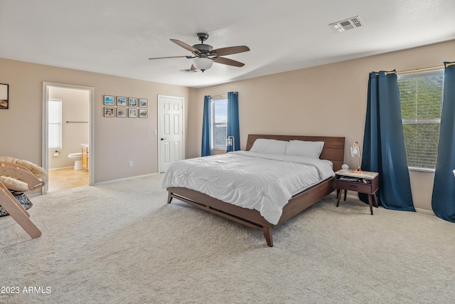 bedroom with ceiling fan, light carpet, and connected bathroom