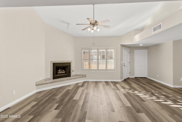 unfurnished living room featuring ceiling fan, wood-type flooring, and a tile fireplace