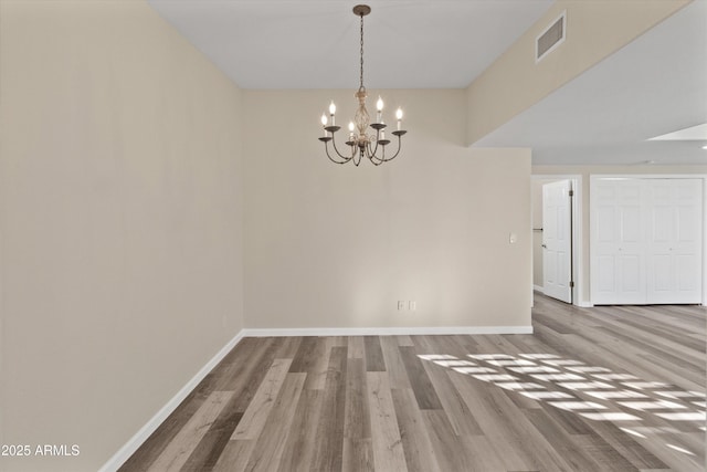 unfurnished dining area with hardwood / wood-style flooring and a notable chandelier