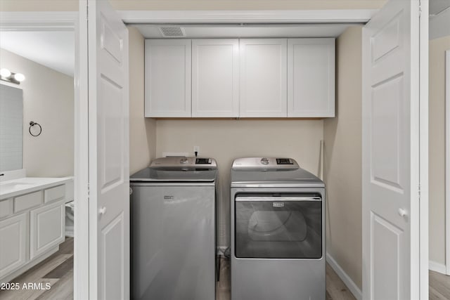 washroom featuring cabinets, washer and dryer, and light hardwood / wood-style floors