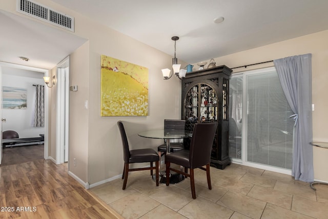 dining space featuring baseboards, visible vents, and a notable chandelier