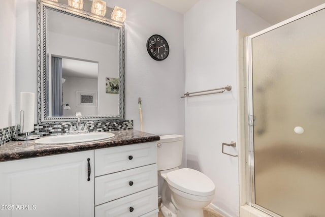 bathroom featuring toilet, backsplash, a shower stall, and vanity