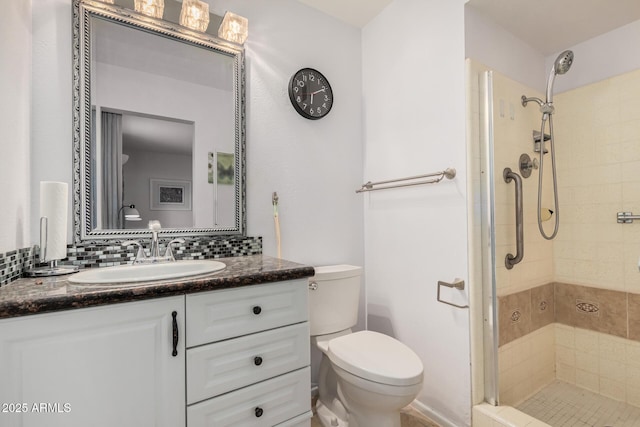 bathroom featuring tasteful backsplash, a shower stall, toilet, and vanity