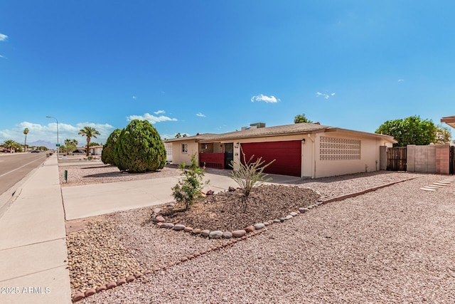 ranch-style house featuring a garage, driveway, and fence