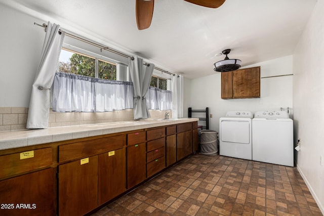 washroom featuring washing machine and dryer, a sink, baseboards, brick patterned floor, and cabinet space