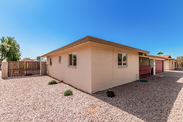 view of property exterior with a garage and fence