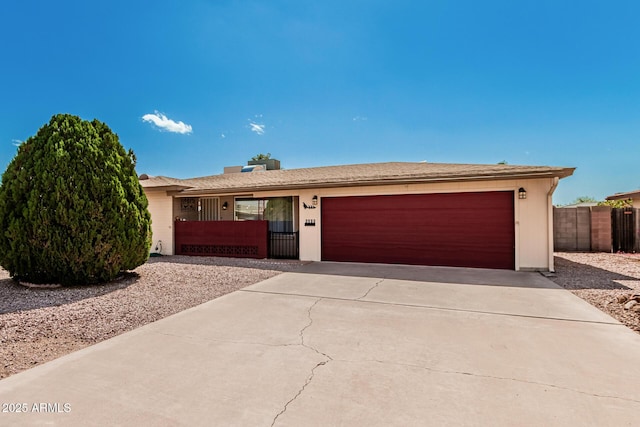 single story home featuring a garage, concrete driveway, and fence