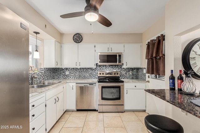 kitchen featuring light tile patterned floors, stainless steel appliances, tasteful backsplash, white cabinetry, and a sink