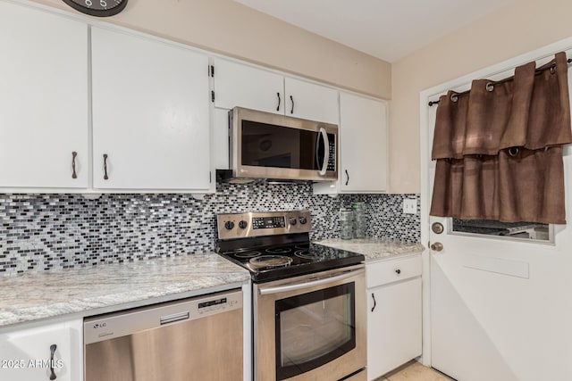 kitchen featuring light stone counters, appliances with stainless steel finishes, white cabinets, and backsplash