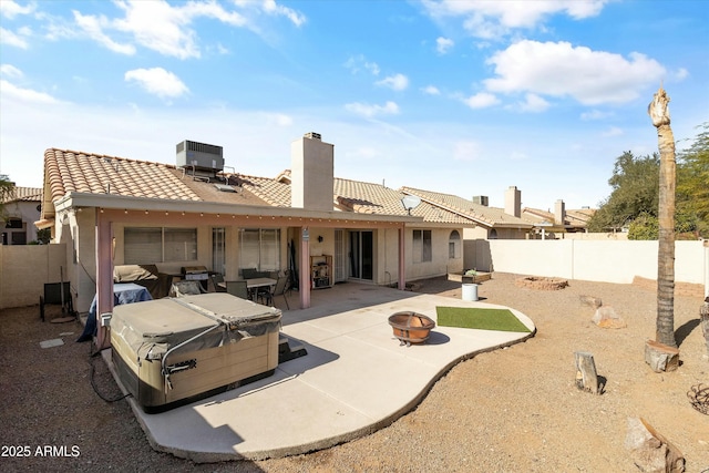 rear view of house with a fire pit, a patio area, a hot tub, and central air condition unit