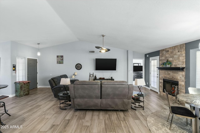 living room featuring lofted ceiling, a large fireplace, and light wood-type flooring