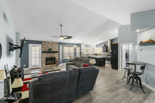 living room with lofted ceiling, a healthy amount of sunlight, a fireplace, and light hardwood / wood-style floors