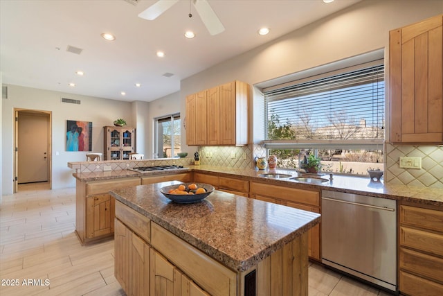 kitchen featuring sink, appliances with stainless steel finishes, tasteful backsplash, a kitchen island, and kitchen peninsula