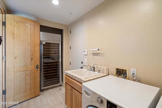 clothes washing area with wine cooler, cabinets, washer / clothes dryer, and sink