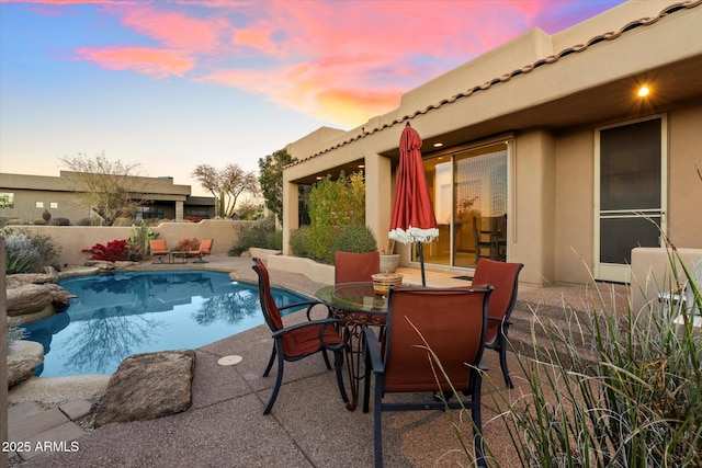 pool at dusk featuring a patio