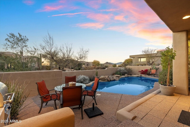 pool at dusk featuring a patio area