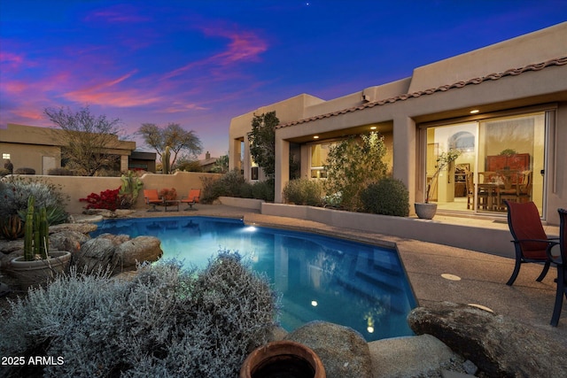 pool at dusk with a patio area