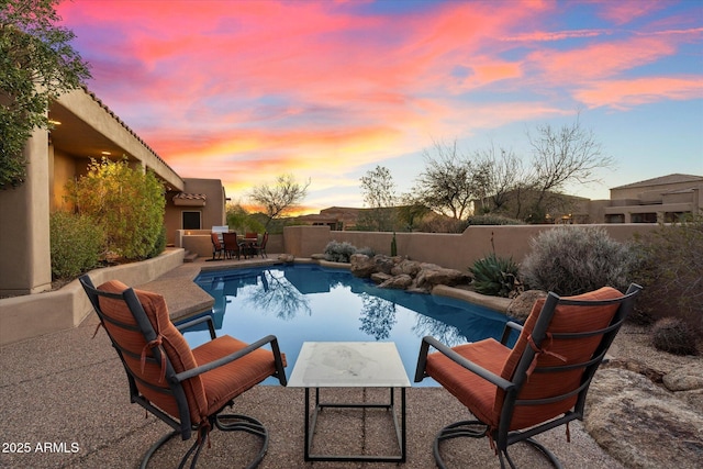 pool at dusk featuring a patio area