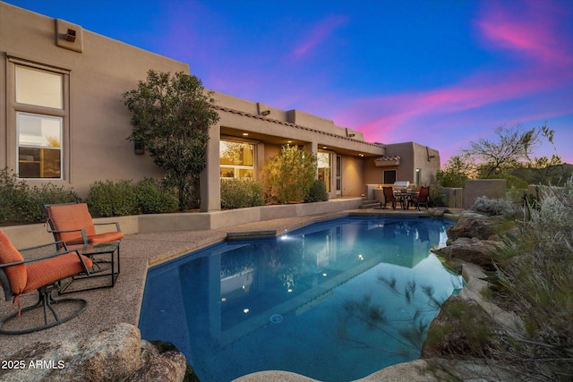 pool at dusk with a patio area