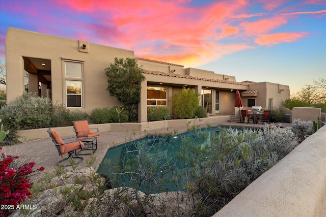 pool at dusk featuring a patio