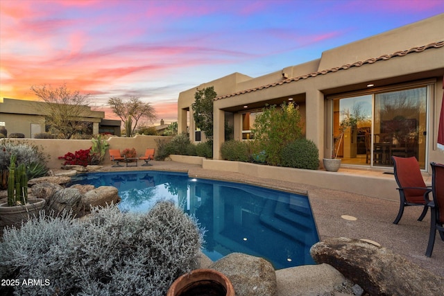 pool at dusk featuring a patio