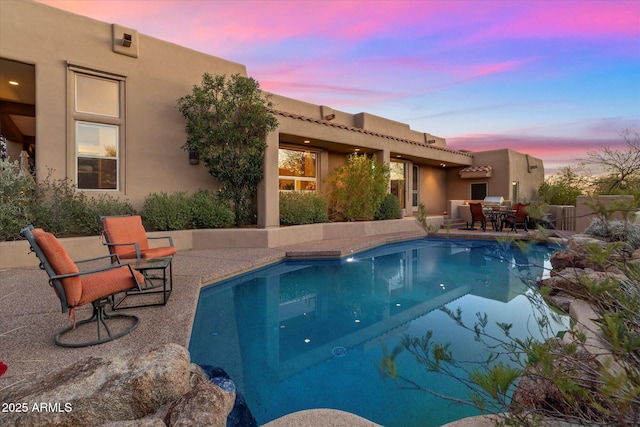 pool at dusk featuring a patio area