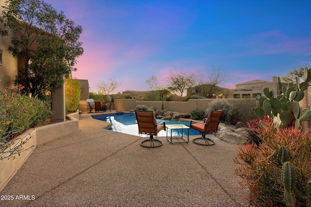 pool at dusk featuring a patio