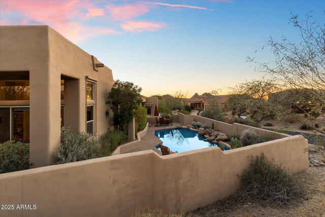 pool at dusk featuring a patio