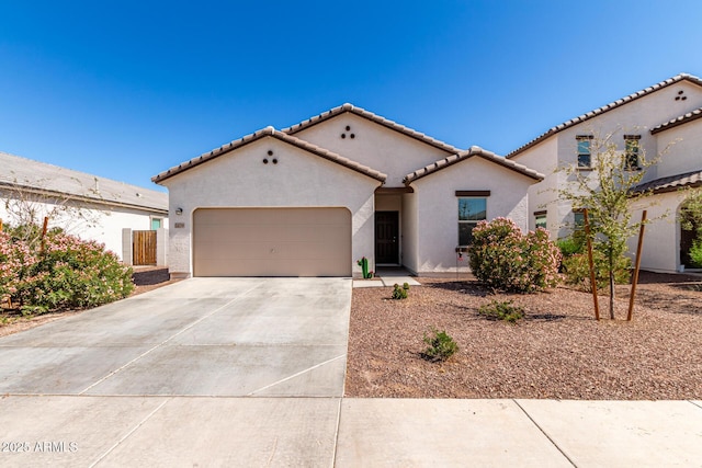 mediterranean / spanish home with a garage, driveway, a tile roof, and stucco siding