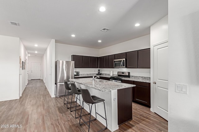 5875 N 195th Dr, Litchfield Park, AZ 85340 - kitchen with stainless steel appliances, visible vents, dark brown cabinets, and light wood finished floors