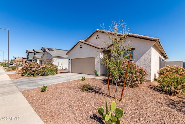 view of front of property featuring a garage, a tile roof, concrete driveway, and stucco siding