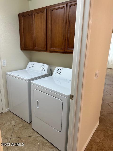 laundry area featuring cabinets, washer and dryer, and light tile patterned flooring