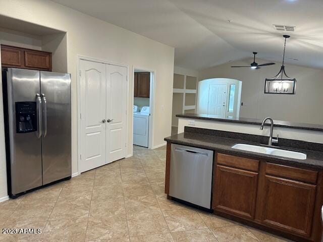 kitchen featuring sink, vaulted ceiling, hanging light fixtures, appliances with stainless steel finishes, and washing machine and dryer