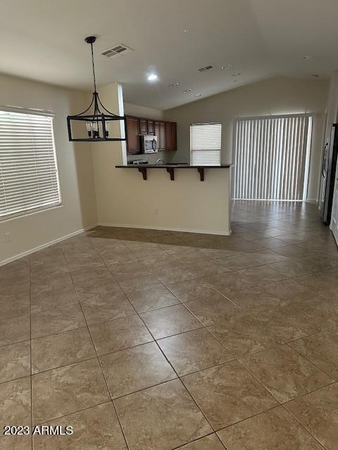 interior space with lofted ceiling, a notable chandelier, and tile patterned floors