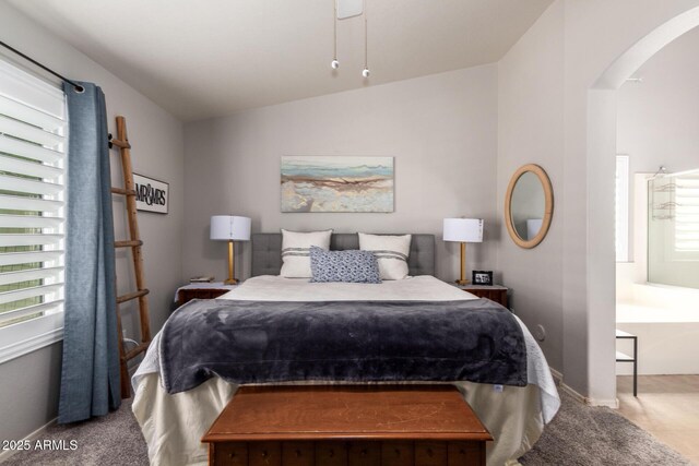 bedroom featuring arched walkways, vaulted ceiling, and baseboards